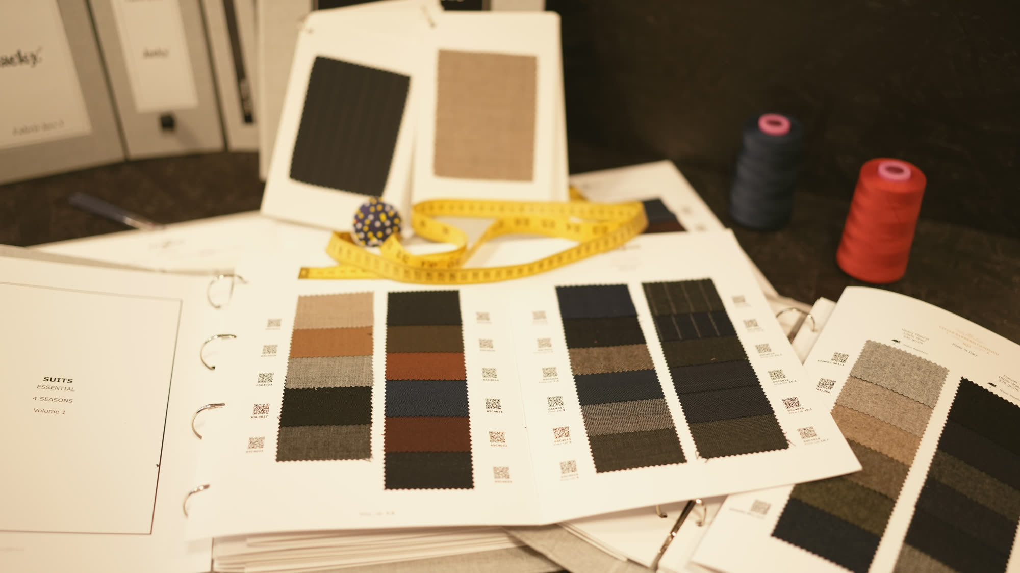 Étoffes, cartes de couleurs et bobines de fil étalées à l’atelier