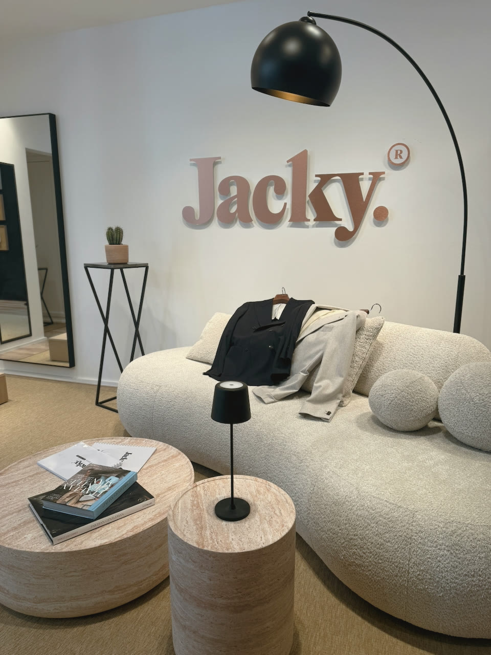 L’intérieur de la boutique Jacky : canapé bouclé, lampe arc et logo au mur